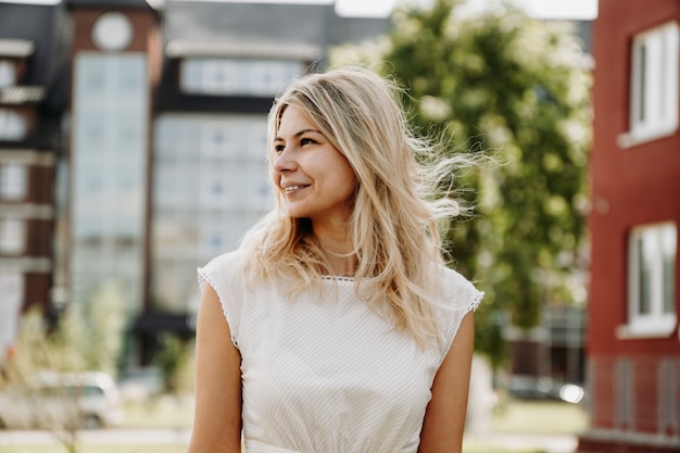 Uma jovem loira com um vestido branco no fundo de uma cidade europeia. O conceito de estilo de vida e felicidade