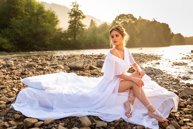 Uma jovem loira esguia em um vestido branco no rio