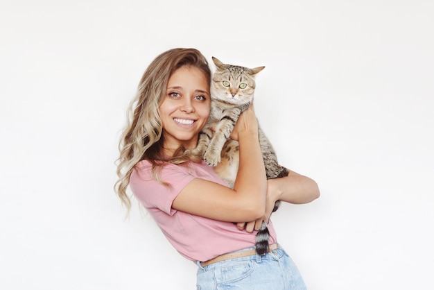 Uma jovem loira sorridente com cabelos ondulados segurando um jovem e adorável gato tabby em suas mãos