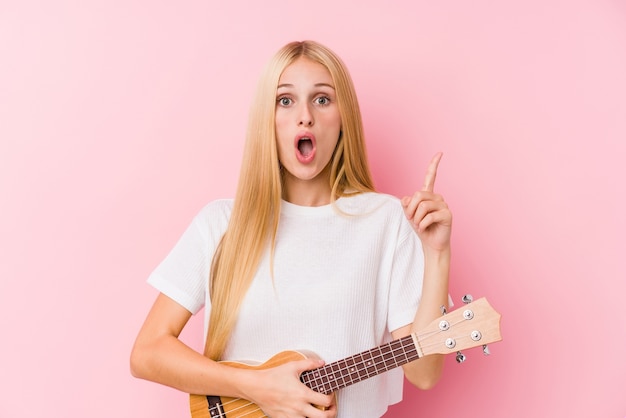 Uma jovem loira tocando ukelele tendo uma ótima ideia