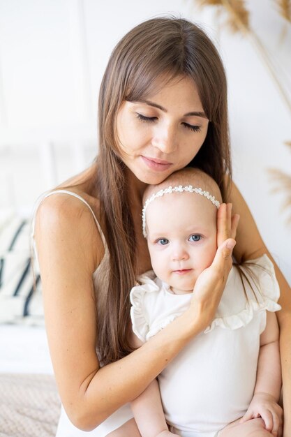 Uma jovem mãe abraça gentilmente sua filha bebê segurando-a em seus braços e abraçando sua mãe amorosa e carinhosa