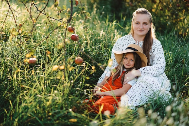 Foto uma jovem mãe abraçando a filha no jardim ao pôr do sol