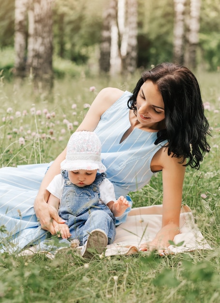 Uma jovem mãe brinca no parque na grama com sua filha