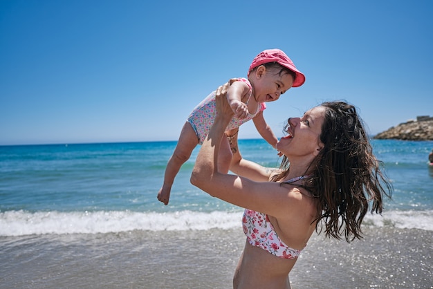 Uma jovem mãe brincando com seu bebê à beira-mar