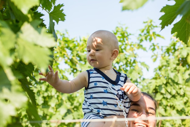 Uma jovem mãe com uma criança pequena em um vinhedo no verão