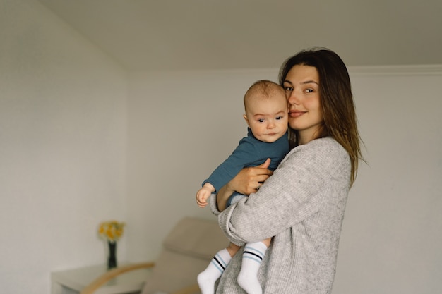 Uma jovem mãe é brincar com o menino. Mãe de um bebê que está amamentando. Feliz maternidade. A família está em casa Retrato de uma feliz mãe e filho.