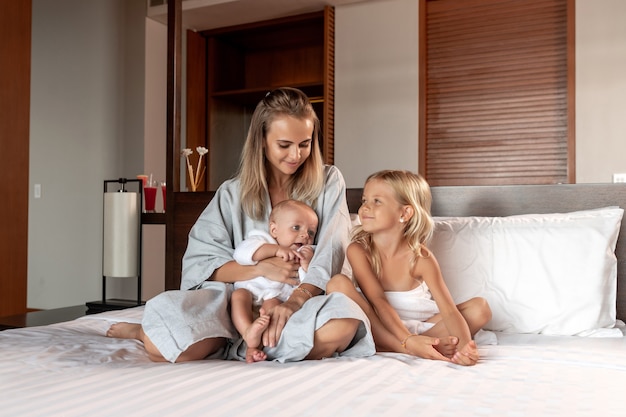 Uma jovem mãe e dois filhos estão sentados na cama