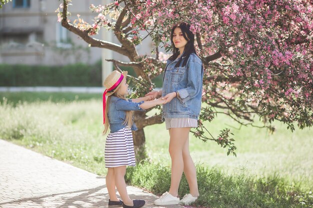 Uma jovem mãe e sua filha pequena no fundo da primavera