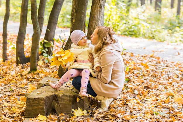 Uma jovem mãe e sua filha se divertem no outono