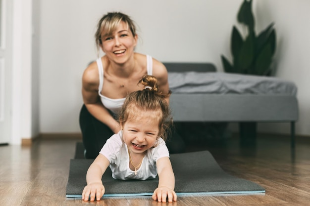 Uma jovem mãe e sua filha se divertem no tapete antes de jogar esportes