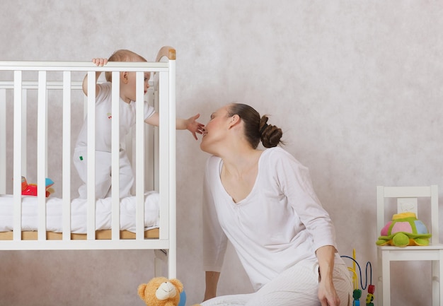 Foto uma jovem mãe entre 30 e 40 anos está brincando com sua filha pequena, que fica em sua cama