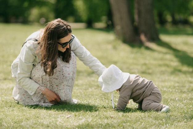 Foto uma jovem mãe está brincando com a filha do mês no prado