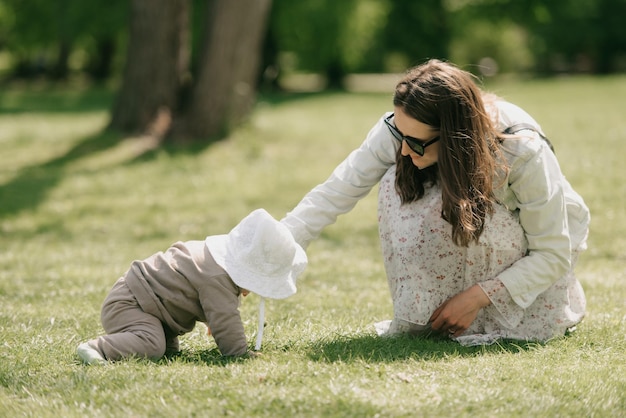Uma jovem mãe está brincando com sua filha de 7 meses no prado