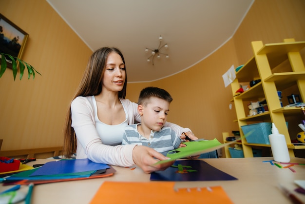 Uma jovem mãe está fazendo lição de casa com o filho em casa