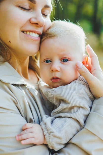 Uma jovem mãe feliz abraça seu filho no sol em um dia quente de primavera ou verão no parque O sol brilha em um pomar ou em um parque Conceito de família de mãe e filho na natureza