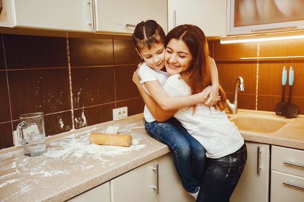 uma jovem mãe fica na cozinha e trabalha com farinha junto com seu filho