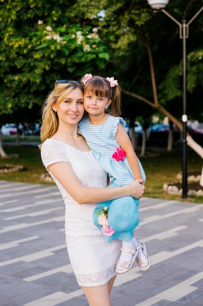 Uma jovem mãe segura sua filhinha em seus braços um forte abraço amoroso