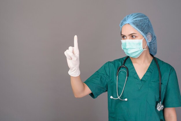 Uma jovem médica confiante de uniforme verde usando máscara cirúrgica