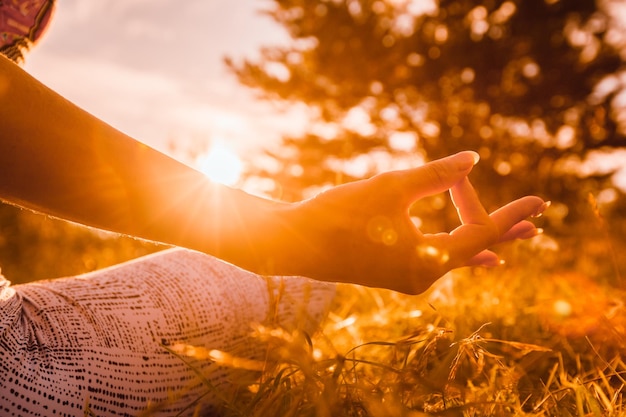 Uma jovem medita e relaxa ao pôr do sol ou nascer do sol.