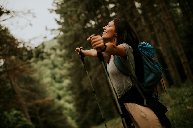 Foto uma jovem mochileira desfrutando de uma bela floresta verde ao seu redor