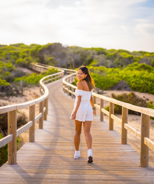 Uma jovem morena caucasiana aproveitando as férias de praia em um vestido branco no verão