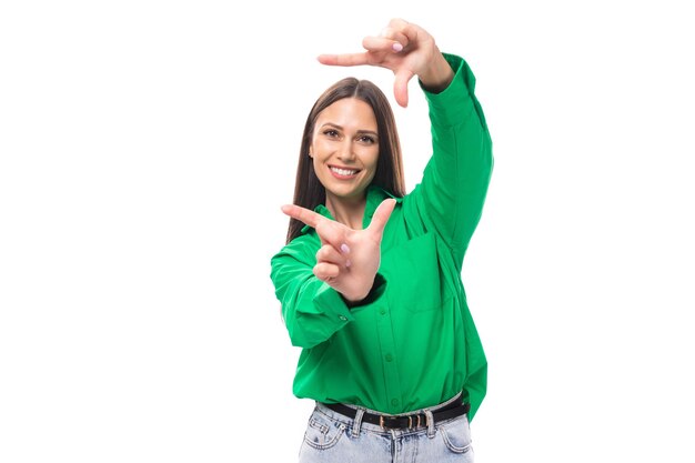 Foto uma jovem morena caucasiana com maquiagem vestida com uma camisa verde e jeans posando em um