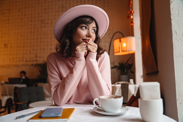 uma jovem morena linda muito linda dentro de casa sente-se no café.