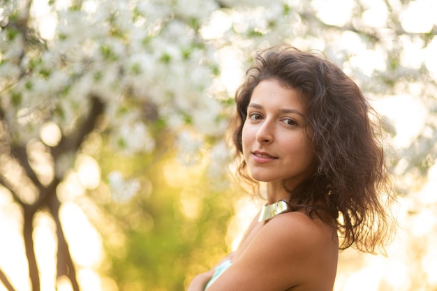 Uma jovem morena posa com um ramo de cerejeira florescendo