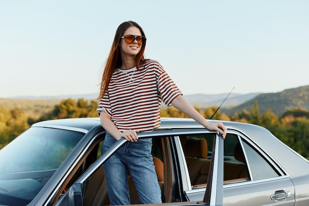 Uma jovem motorista olha para fora do carro para a paisagem de outono e sorri satisfatoriamente