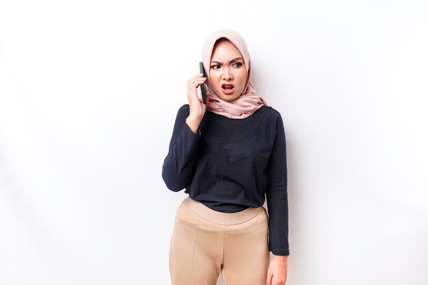 Uma jovem muçulmana asiática insatisfeita falando ao telefone parece descontente com expressões faciais irritadas que mostram uma atitude negativa