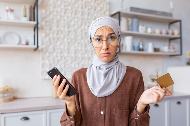 Uma jovem muçulmana chateada usando hijab sentindo frustração e problemas com a conta do cartão de crédito e