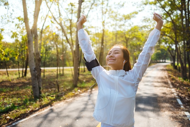 Foto uma jovem mulher asiática esticando os braços antes de correr no parque da cidade