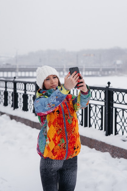 Uma jovem mulher atlética tira uma selfie em um dia gelado e com neve. fitness, recreação