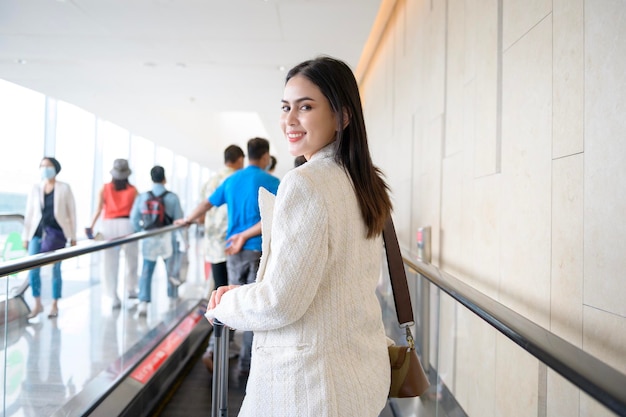 Uma jovem mulher bonita andando com mala de check-in no aeroporto internacional