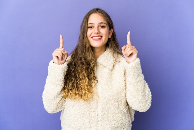 Uma jovem mulher bonita indica com os dois dedos indicadores para cima, mostrando um espaço em branco