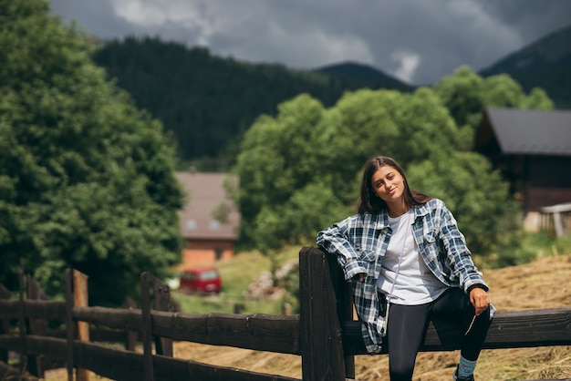 Uma jovem mulher branca e atraente sentada em uma cerca