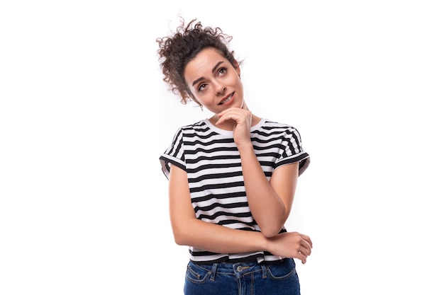 Uma jovem mulher caucasiana com cabelo encaracolado vestida com uma camiseta de verão a listras está a fazer brainstorming