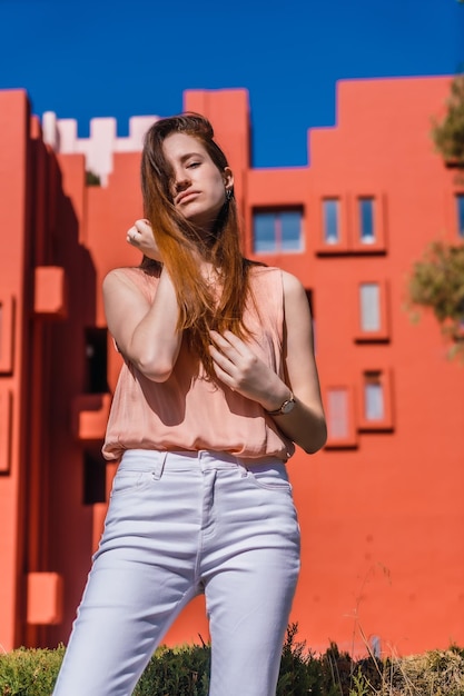 Uma jovem mulher caucasiana em uma camisa cor de salmão e calças brancas em um verão