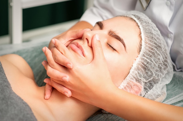 Uma jovem mulher caucasiana, recebendo massagem facial em um spa.