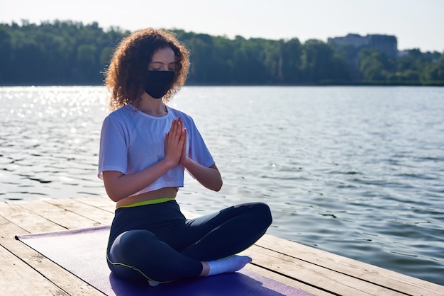 Uma jovem mulher com cabelos cacheados, fazendo yoga fora