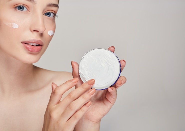 Foto uma jovem mulher com olhos azuis, olhando para a câmera e toca o creme com o dedo. atendimento domiciliar.