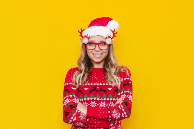 Uma jovem mulher com um suéter de cervo e chapéu de Papai Noel vermelho cruza os braços sobre o estômago