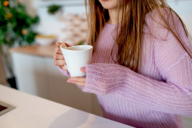 Foto uma jovem mulher com um suéter rosa mantém a xícara de café, close-up