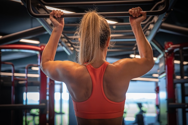 Uma jovem mulher com uma figura de esportes praticando no ginásio, fitness e musculação