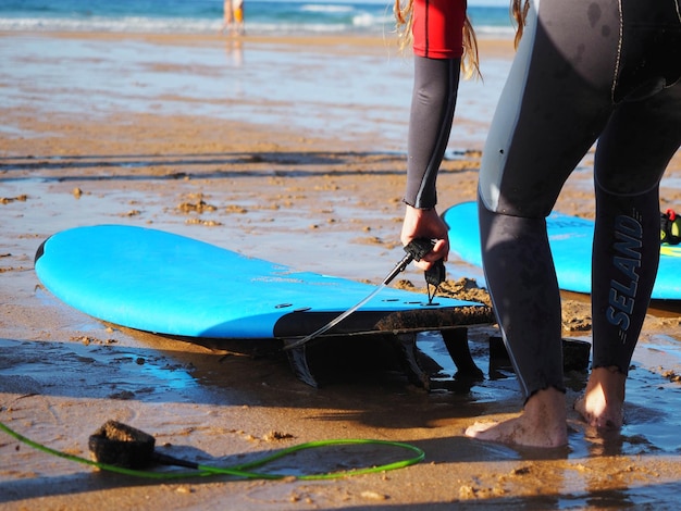Uma jovem mulher com uma prancha de surf azul na beira-mar em close-up