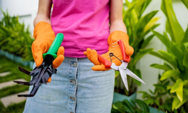 Uma jovem mulher cuida do jardim, rega, fertiliza e pruneia as plantas.