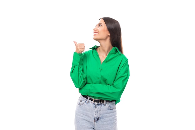 uma jovem mulher de negócios morena com uma camisa verde mostra sua mão para o lado em um fundo branco com espaço de cópia