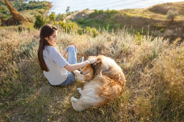 Uma jovem mulher e um cachorro idoso caminham pelo campo em uma noite de verão. Uma senhora e seu fiel amigo de infância um cachorro collie