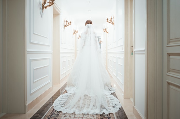 Uma jovem mulher em um vestido branco andando por um corredor branco