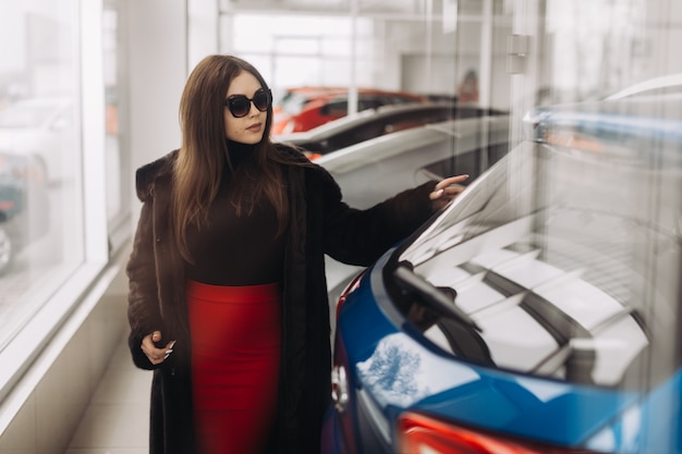 Uma jovem mulher está escolhendo um carro novo na loja de carros
